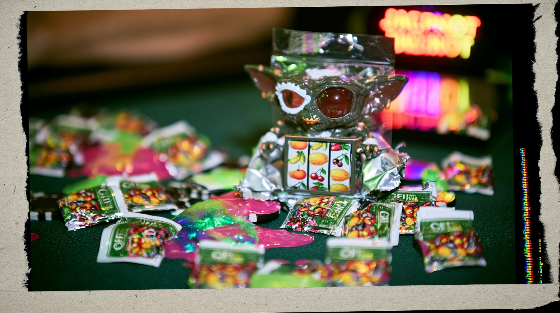A torn blind box foil pouch on casino felt with a slot-machine creature emerging.